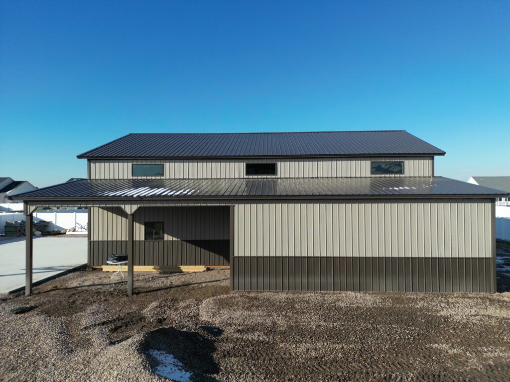 Partially open and closed lean-to on a pole barn, with remnants of snow on the roof, highlighting versatile design and seasonal durability.