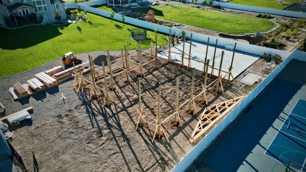 Poles positioned in holes, ready for concrete pouring, marking the initial phase of framing a new pole barn structure.