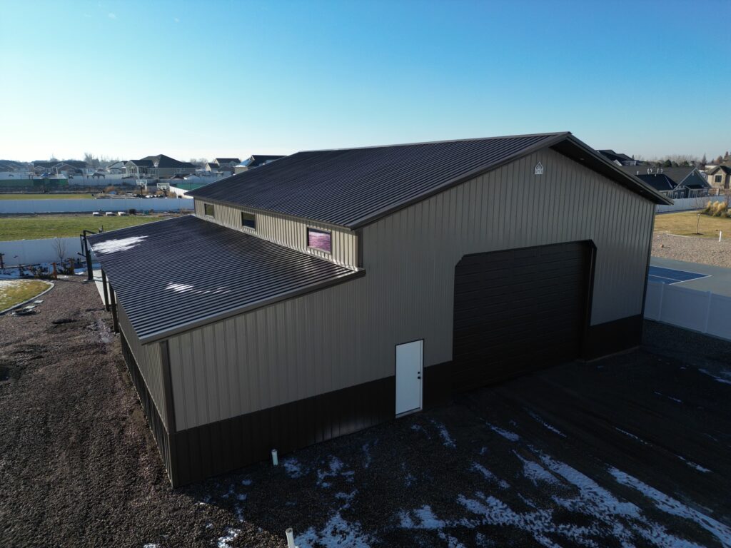 Spacious pole barn and lean-to with a sturdy metal roof and large garage door, set against a backdrop of clear blue skies.